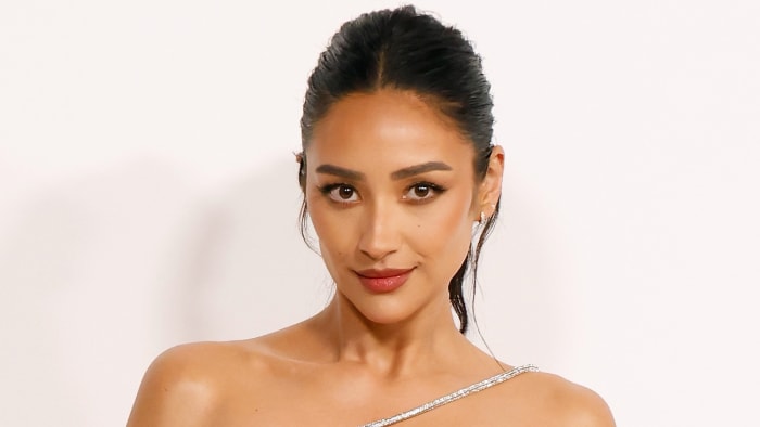 Shay Mitchell poses in an off-the-shoulder dress and a slicked back up-do.
